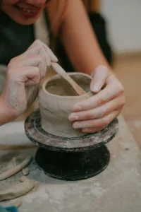 Een jonge vrouw is aan het handvormen, ze maakt een hoge schaal door te werken met de coiling techniek